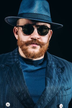A close up portrait of a stylish man in sunglasses posing in the studio over the black background. Men's beauty, fashion, style, optics.の写真素材