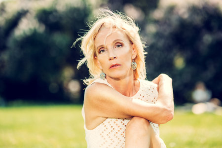 A portrait of an elderly woman relaxing on the grass in the summer park. Beauty, healthcare.