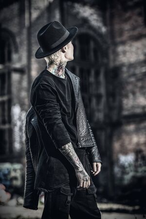 A bright portrait of an extravagant young asian guy walking around the ruins. Summer, beauty, bodyart, tattoos, fashion.の写真素材