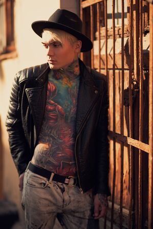 A bright portrait of an extravagant young asian guy with tattoos on the body walking in the street. Summer, beauty, bodyart, tattoos, fashion.の写真素材