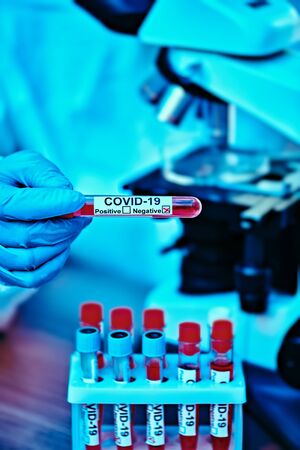COVID-19. Doctor, microbiologist, scientist in a protective suit, makes a research on blood samples of infected people in the laboratory. Coronavirus test.の写真素材