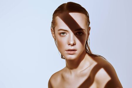 Beauty concept. Portrait of a beautiful young woman with fresh natural make-up and perfect healthy skin. The play of light and shadow. Fashion. Copy space.の写真素材