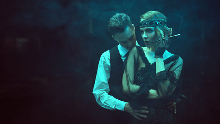 Glamorous passionate couple of a man and a woman in the style of 1920s in a dark smoky interior....