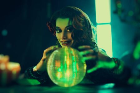 Bewitching fortune teller woman reading future on magical crystal ball.の写真素材