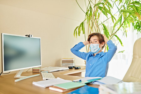 Coronavirus and life. Boy schoolboy student scared holding his head remotely learning at home due to...