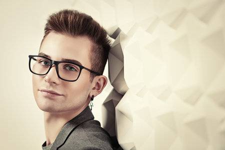 Portrait of a smart young man in a suit and glasses. Studio shot. Men's beauty.