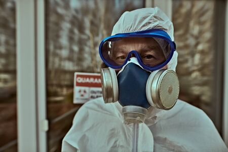 Coronavirus concept. Portrait of the emergency doctor in a protective suit, glasses and respiratory mask standing on a street.の写真素材