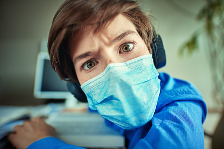 COVID-19 or coronavirus concept. A boy in a medical mask looks into the camera with big surprised...