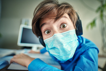COVID-19 or coronavirus concept. A boy in a medical mask stares intently at the camera while being...