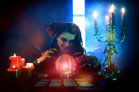 Magnificent fortune teller woman reading future on magical crystal ball and tarot cards.の写真素材