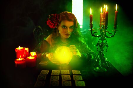 Magnificent fortune teller woman reading future on magical crystal ball and tarot cards.の写真素材