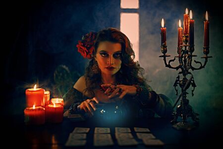 Magnificent fortune teller woman reading future on magical crystal ball and tarot cards.の写真素材