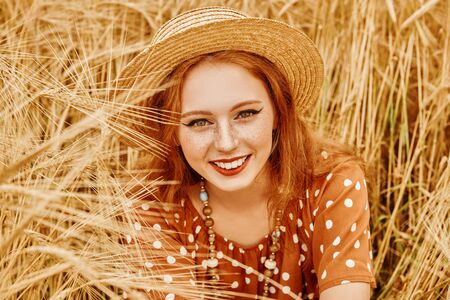 Romantic hippie girl sitting on a wheat field. Summer. Hippie, bohemian style.の写真素材