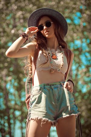 Outdoor portrait of a pretty modern hipster hippie girl. Spirit of freedom and adventures. Summer holidays.の写真素材