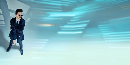 Modern stylish man in elegant black suit, white shirt and sunglasses posing on a grey background with shadows. Full length portrait of a modern businessman. Men's fashion.の写真素材