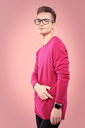 Youth fashion. Happy young guy in modern clothes is posing on a pink background. Study, education.の写真素材