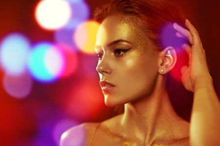 Golden make-up. Portrait of a beautiful young woman with golden make-up on a black background. Luxurious style. Cosmetics and make-up concept.の写真素材