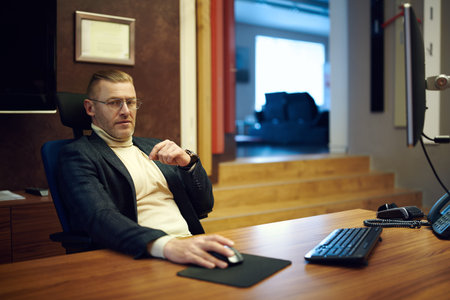 Respectable middle-aged businessman in a suit and glasses works in a modern office. Successful...