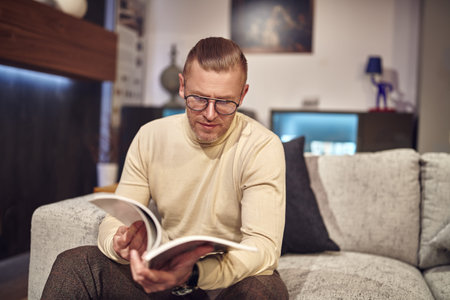 Handsome middle-aged man in elegant casual clothes and glasses having a rest at home. Success and...