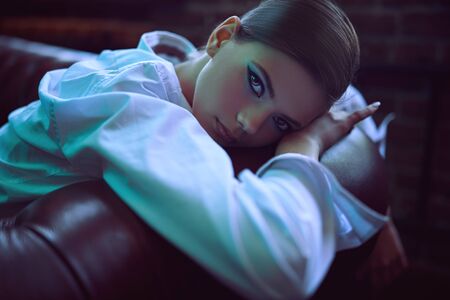 Close-up portrait of a gorgeous brunette girl with beautiful brown eyes. Fashionable female model posing in a luxurious apartments. Make-up and cosmetics.の写真素材