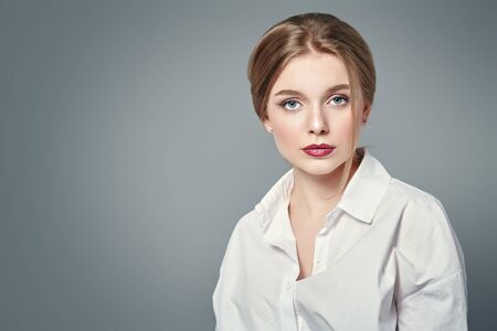 Portrait of a beautiful young woman with blonde hair and natural make-up. Studio shot on a gray background. Beauty industry.の写真素材