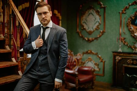 Handsome gentleman poses in a tweed suit and glasses in a vintage interior. Luxurious lifestyle. Vintage style. の写真素材