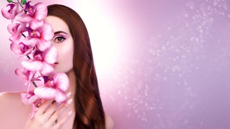 Beauty woman. Portrait of a beautiful  young woman with orchid flowers. Make-up and cosmetics. Beauty and health care.の写真素材