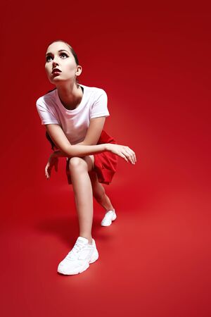 Sportswear fashion. Beautiful athletic girl model posing in modern sportswear on a red background at studio.の写真素材