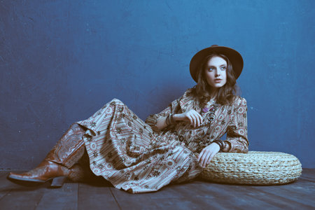 Fashion shot of a gorgeous young woman in boho style dress and accessories posing at studio....