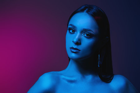 Beauty, Fashion concept. Portrait of an attractive brunette girl posing in color mixed light. Makeup and cosmetics, jewelry. Studio shot.の写真素材