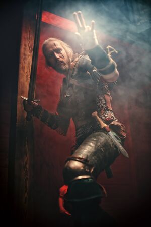 Fantasy medieval knight in armor is fighting with a sword in his hands. The Witcher man.の写真素材