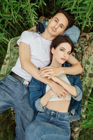 Portrait of a young couple in love, relaxing on the fresh air in nature lying on green grass. People in love. Summertime.の写真素材