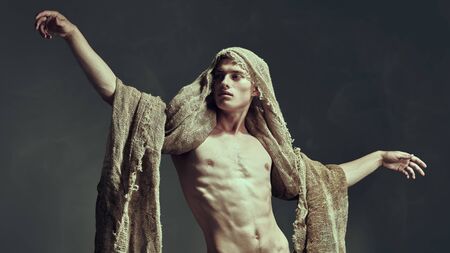 Male beauty concept. Art portrait of of a courageous muscular man with burlap on his face and body. Studio shot on a black background.の写真素材