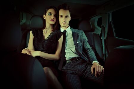 Fashionable couple of young people in the car. Glamorous lifestyle, night party.