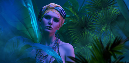 Portrait of a beautiful fashionable woman wearing beads and a scarf on her head standing among...