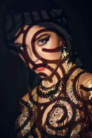 Oriental fairy tale. Portrait of a beautiful arab woman with traditional make-up and black hijab. Make-up and cosmetics.の写真素材