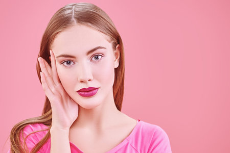 Cute girl teenager in a pink t-shirt posing on a pink background. Copy space. Youth style. Cosmetics...