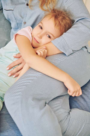 Little girl falls asleep in the bedroom in the arms of her mom. Happy family and love concept.の写真素材
