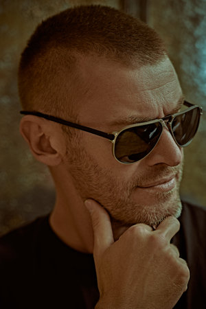 Portrait of a handsome brutal mature man with short hair and bristles wearing trendy sunglasses....