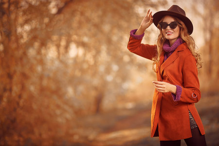 Beautiful young woman walks through the autumn park and smiles. Autumn beauty, fashion.