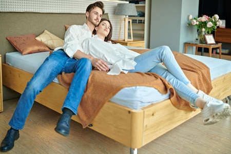 Handsome young couple is resting on the bed in the bedroom at home. Home interior, furniture.の写真素材