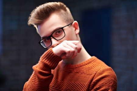 Portrait of a smart young guy in a pullover and glasses. Studio shot. Men's beauty. Study,...