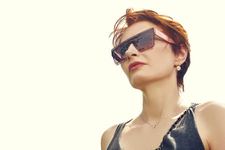 Modern business woman in stylish sunglasses is against a bright sky on a sunny day. Optics for...