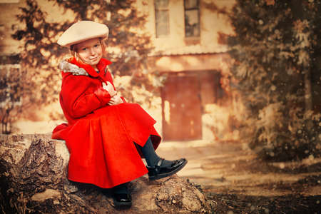 Elegant little girl sittingon the background of the house on a sunny day. Children's fashion.の写真素材