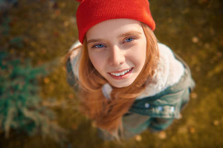 Happy teen girl in a beautiful autumn park looks up to the camera and smiles.の写真素材