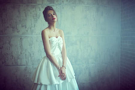 Portrait of a beautiful fashion model in a luxury wedding dress posing at studio on a grunge background. Wedding fashion.の写真素材