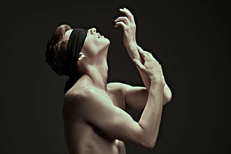 Art portrait of a handsome athletic young blindfold man with perfect muscular body. Men's beauty and health. Copy space.の写真素材