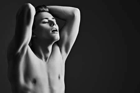 Black-and-white portrait of a handsome athletic young man with perfect muscular body. Sports and bodybuilding. Men's beauty and health.の写真素材