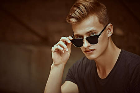 Handsome young man in sunglasses and black t-shirt outdoor. Urban grunge style. Male fashion.の写真素材