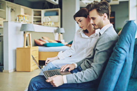 Beautiful young people in love spending time together at home. Happy couple. Home interior, furniture.の写真素材